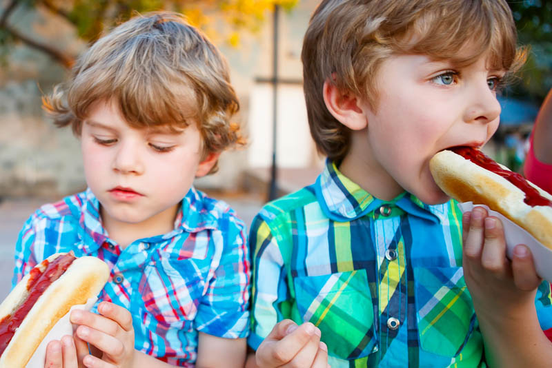 Image of two children eating hotdogs.